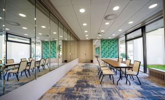 a long , narrow room with a long table and chairs is surrounded by large mirrors on the walls at Hotel Holiday