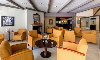 a spacious room with a fireplace , yellow chairs , and a round table in the center at Fletcher Hotel-Restaurant de Klepperman