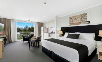 a hotel room with a king - sized bed , a television , and a balcony overlooking a city view at The Wellington Apartment Hotel