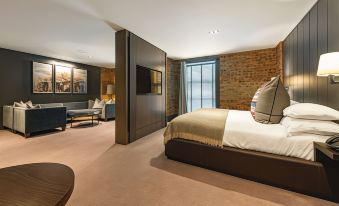 a luxurious bedroom with a king - sized bed , a flat - screen tv mounted on the wall , and a brick wall at Dakota Eurocentral