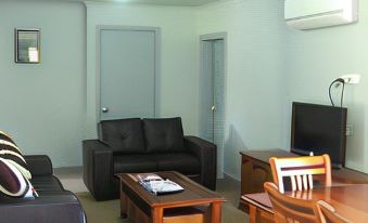 a living room with a couch , chairs , and dining table in front of a window at Seahorse Coastal Villas