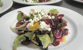 a white plate filled with a delicious salad topped with cheese , sitting on a dining table at Balch Hotel