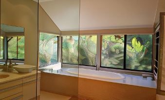 a modern bathroom with a large window that reflects the outdoor scenery , and a white bathtub at Jarrah Grove Forest Retreat