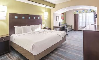 a hotel room with a king - sized bed , a couch , and a television . the room is well - lit and appears to be clean at La Quinta Inn & Suites by Wyndham Dallas Grand Prairie South