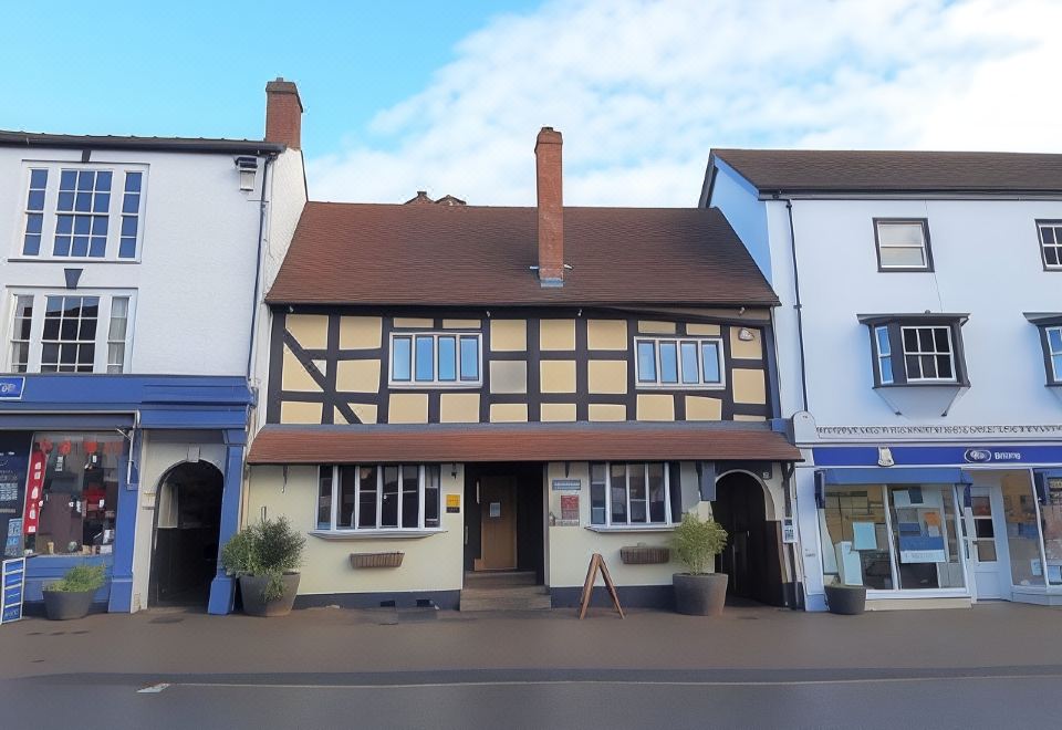 a brick house with a red roof and a chimney is shown in front of other buildings at Seven Stars