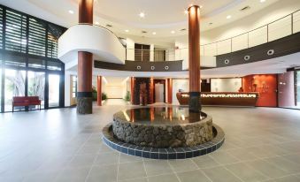 a large , modern lobby with a circular fountain in the center and wooden columns on either side at Te Moana Tahiti Resort