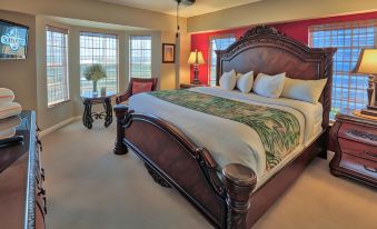 a large bed with a wooden headboard and footboard is in the middle of a room with windows at Ocean Pointe Suites at Key Largo