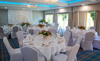 a well - decorated banquet hall with multiple round tables and chairs , all set for a formal event at Alton House Hotel