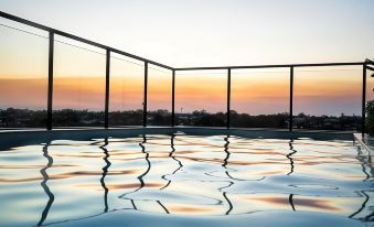 a large , empty swimming pool with a reflection of the sky in the water at sunset at The Sebel Brisbane Margate Beach