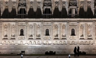 a large building with intricate carvings on its facade , illuminated by street lights at night at Parador de Leon - San Marcos