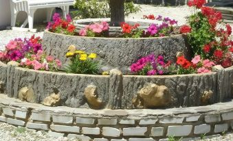 a stone wall with a circular planter filled with colorful flowers , creating a beautiful and inviting atmosphere at Stella Marina