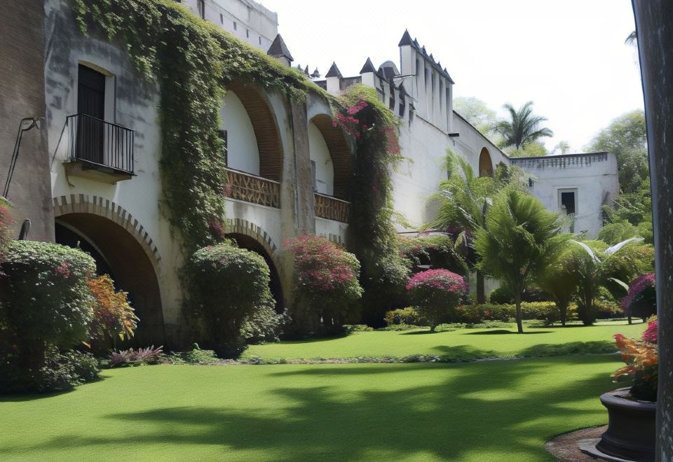 a white building with ivy growing on its walls , surrounded by lush greenery and palm trees at Hotel Hacienda Vista Hermosa