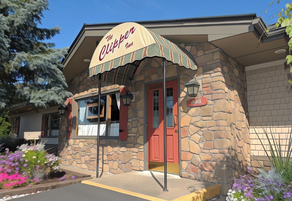 "the exterior of the "" clipper "" restaurant , a modern restaurant with stone walls , green awnings , and red - tiled roof , under" at The Clipper Inn