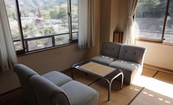a cozy living room with two gray couches and a wooden coffee table in front of a window overlooking a beautiful view at Jukeiso