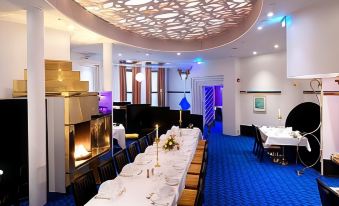 a long dining table with white tablecloths and chairs is set up in a room with blue carpet at Thon Hotel Oslofjord
