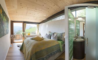 a bed with yellow and blue bedding is situated in a bedroom with wooden walls and large windows at The View
