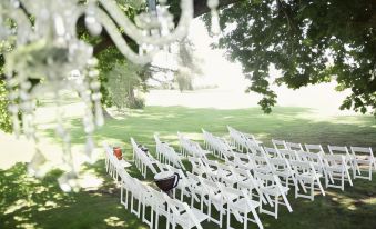 a row of white chairs set up in a grassy field , ready for a wedding ceremony at Quamby Estate