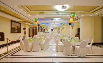 a large banquet hall with multiple tables set up for a formal event , possibly a wedding or other party at Semeli Hotel