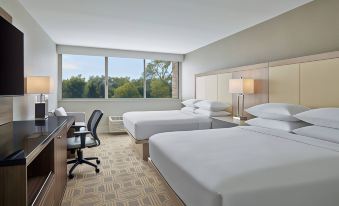 a hotel room with two white beds , a desk , and a chair , all situated near large windows at Delta Hotels Chicago Willowbrook