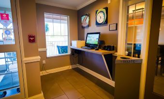 a room with a desk , computer monitor , and other items is shown with a window at Country Inn & Suites by Radisson, Burlington (Elon), NC