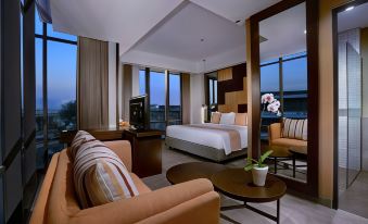 a luxurious hotel room with a large bed , couch , and dining table , all surrounded by comfortable seating at ASTON Inn Mataram