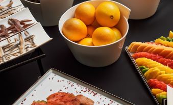 a table is set with various fruits and bowls of fruit , including grapes , oranges , and grapes at Briig Boutique Hotel