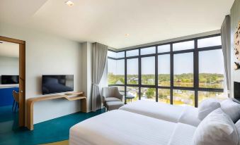 a modern hotel room with a large window , white bed , and tv , providing a view of the outdoors at Na Tree Tara Riverside Resort Amphawa Damnoensaduak