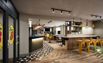 a modern restaurant with a bar and dining area , featuring a checkered tile floor and yellow chairs at Super 8 by Wyndham Chester East