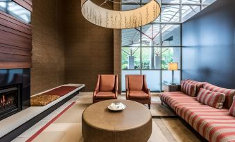 a modern living room with two chairs , a couch , and a coffee table under a hanging light at Waipuna Hotel & Conference Centre