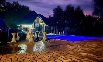 a nighttime scene with a building and its surrounding area lit up , including a pool area and a bridge at River Rock Lodge