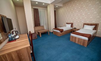 a hotel room with two beds , a desk , and a couch , all neatly arranged on a blue carpet at Continental Hotel