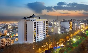 A stunning nighttime view from the rooftop showcases an illuminated clock tower in the foreground, complemented by the city skyline in the background at Espinas International Hotel