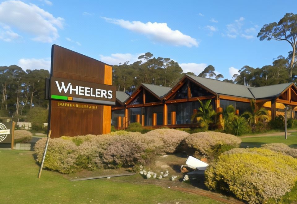 "a large building with the name "" wheelers "" written on it , surrounded by trees and grass" at Fairway Motor Inn