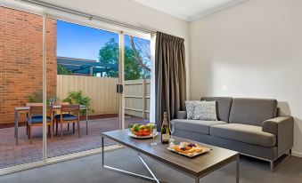 a living room with a couch , coffee table , and sliding glass door leading to an outdoor patio at Quest Brighton on the Bay