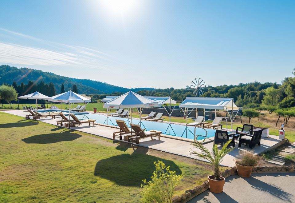 a large outdoor swimming pool surrounded by lounge chairs and umbrellas , with a windmill in the background at Monnaber NOU Finca Hotel & Spa