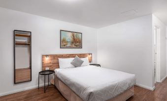 a clean and well - organized bedroom with a white bed , a mirror , and a painting on the wall at Econo Lodge Lilydale