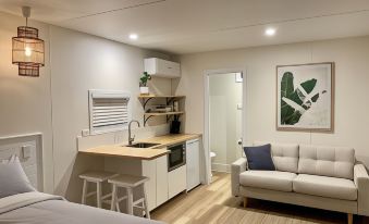a small , modern kitchen and bedroom area with a couch , dining table , sink , and cabinets at Little Palm Cabins