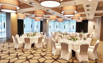 a large , empty banquet hall with multiple white tables and chairs set up for a formal event at Steigenberger Hotel Köln