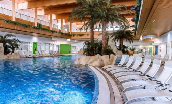 an indoor swimming pool surrounded by lounge chairs and palm trees , creating a relaxing atmosphere at Hotel Diamante