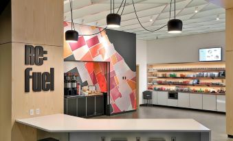 a modern coffee shop with a counter and a colorful mural on the wall , featuring a variety of food options at Aloft Little Rock West