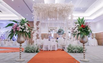 a wedding altar decorated with white flowers and flowers in vases , surrounded by white chairs at Grand Cordela Hotel As Putra Kuningan