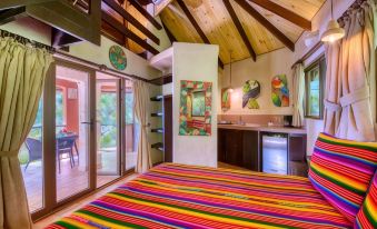 a colorful bedroom with a bed covered in a striped blanket , surrounded by various items such as a dresser , a mirror , and a at Ylang Ylang Beach Resort