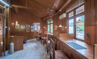 a room with wooden walls and ceiling has several desks , chairs , and windows , as well as framed pictures on the walls at Gangga Island Resort & Spa