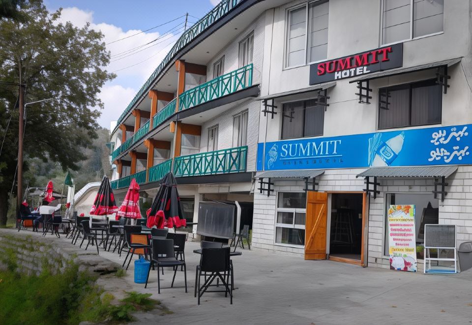 "a building with a blue sign that says "" summit hotel "" and several tables and chairs outside" at Summit Hotel