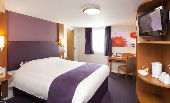 a hotel room with a large bed , purple curtains , and a desk area , decorated with flowers and flowers on the walls at Darlington East (Morton Park)