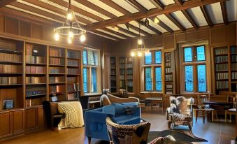 a large room with wooden floors and walls , featuring a bookshelf filled with books and blue couches at The Castle at Skylands Manor