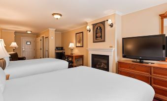 a hotel room with two beds , a fireplace , and a flat - screen tv mounted on the wall at Best Western White House Inn