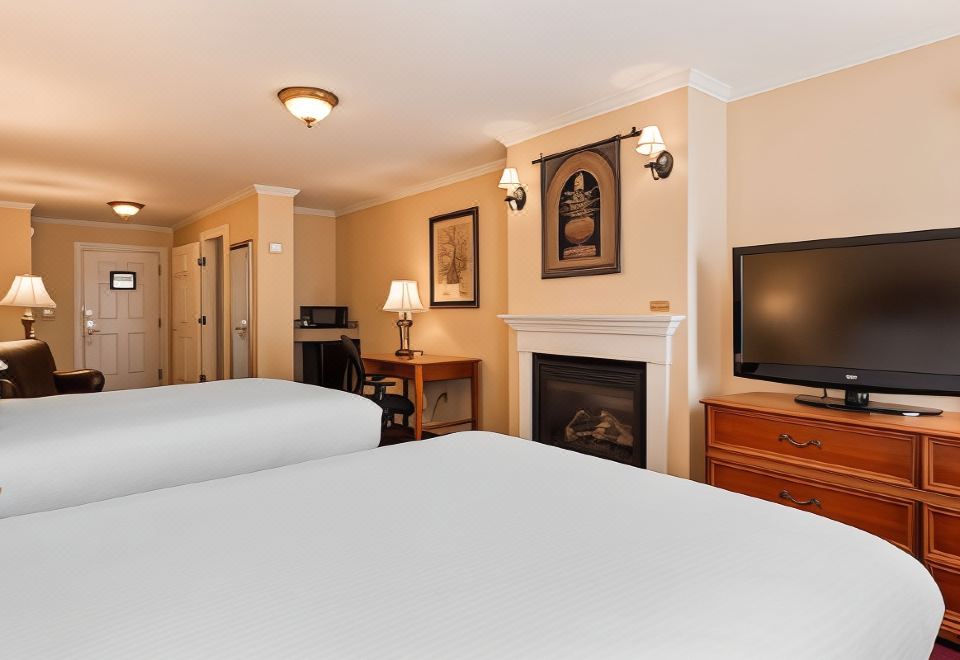 a hotel room with two beds , a fireplace , and a flat - screen tv mounted on the wall at Best Western White House Inn