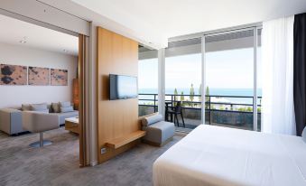 a modern hotel room with a large window offering an ocean view , a bed , and a couch at Chateau Royal Beach Resort & Spa, Noumea