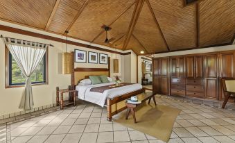 a large bedroom with a wooden ceiling , a king - sized bed , and a dresser in the corner at Sleeping Giant Rainforest Lodge